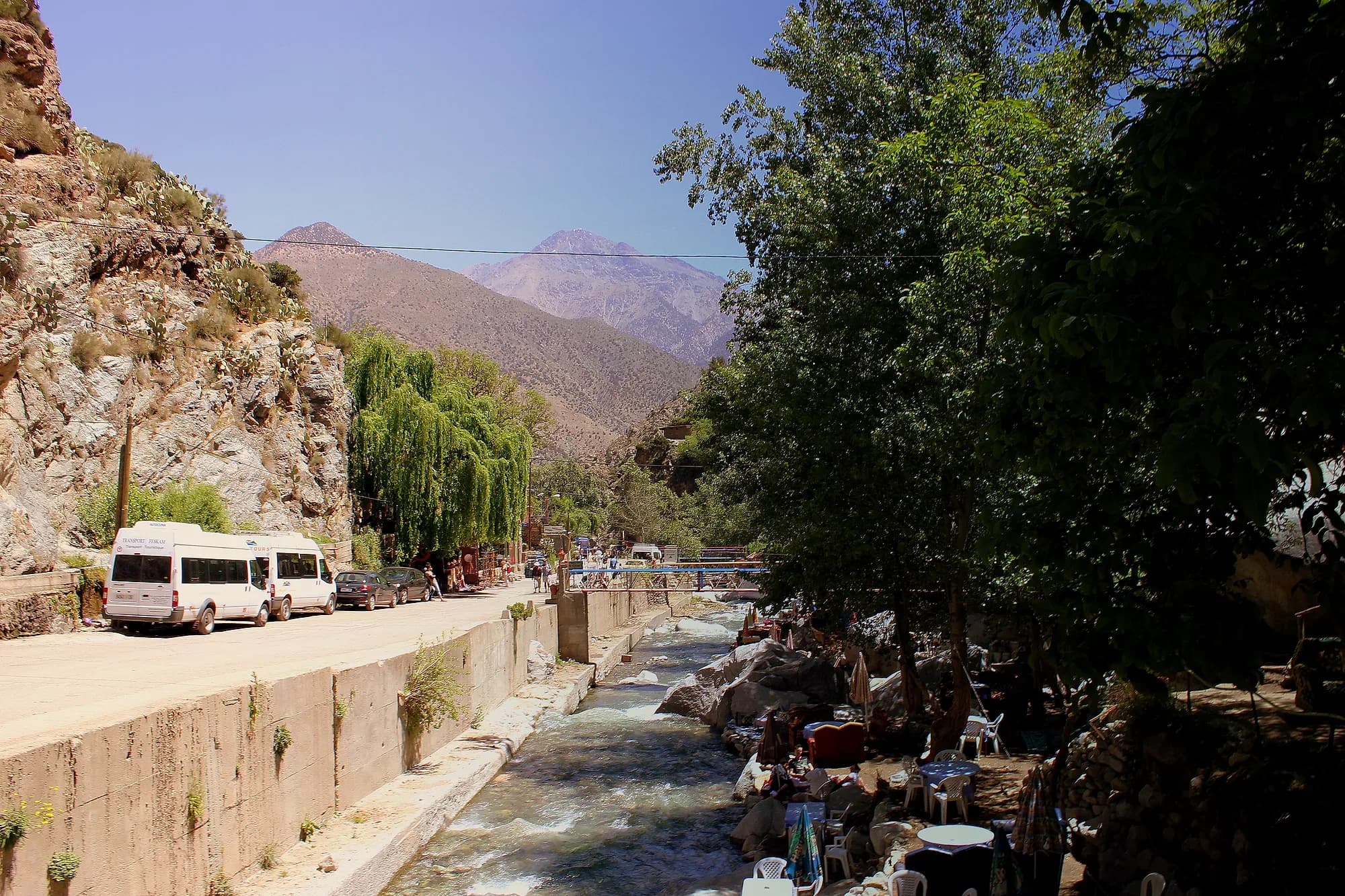 Minibuses blancos aparcados junto a la carretera de un valle del Alto Atlas