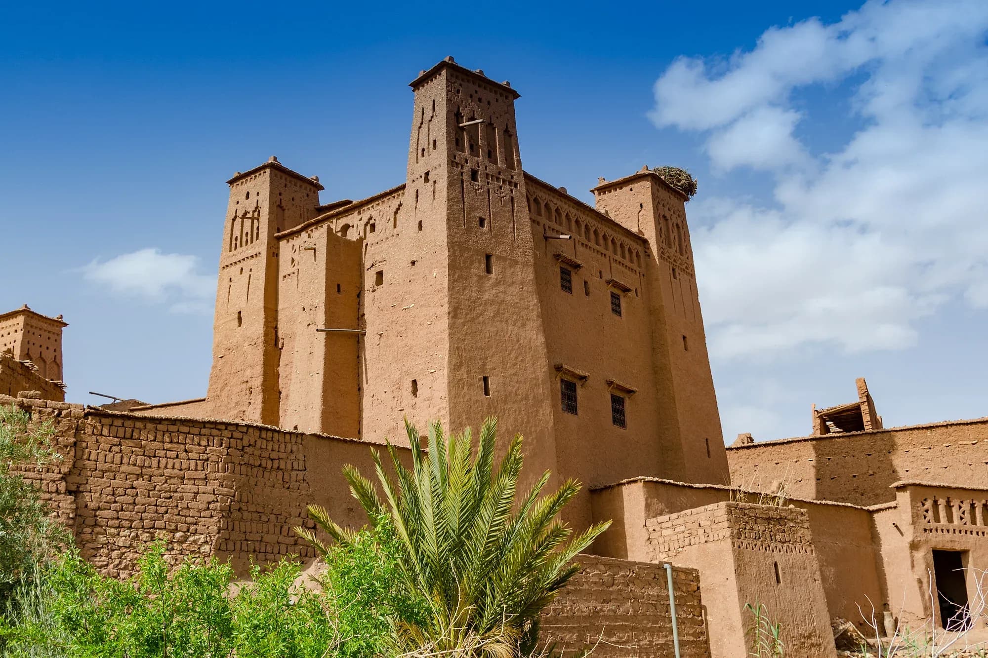 Torres almenadas de una kasbah de adobe en Aït Ben Haddou bajo un cielo azul