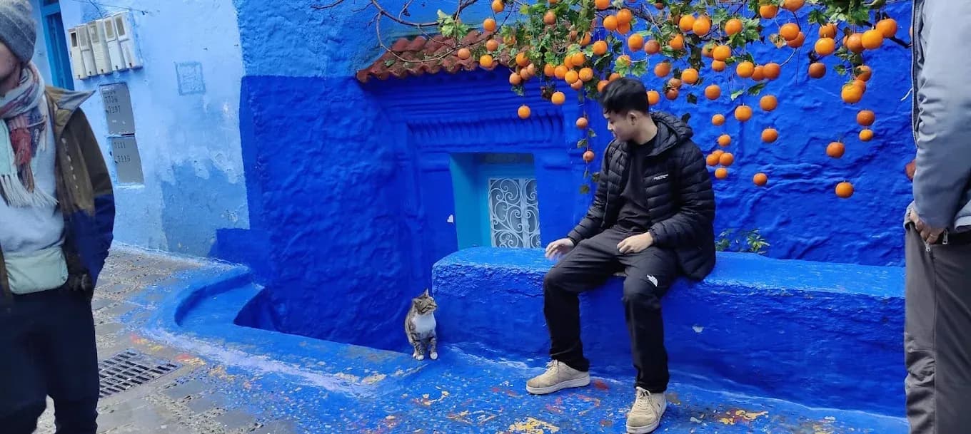 Traveller sitting by a blue wall in Chefchaouen