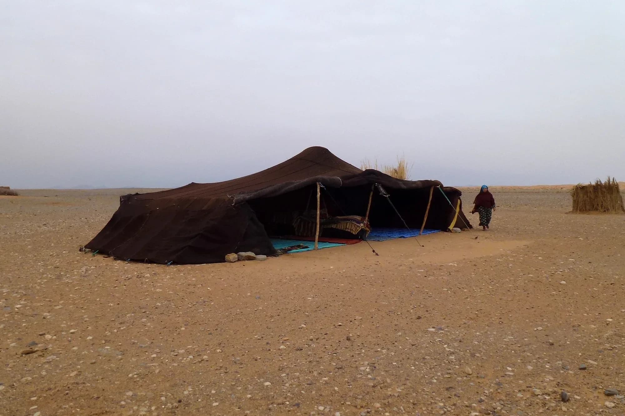 Jaima nómada de lona oscura en la llanura desértica cerca de las dunas de Merzouga
