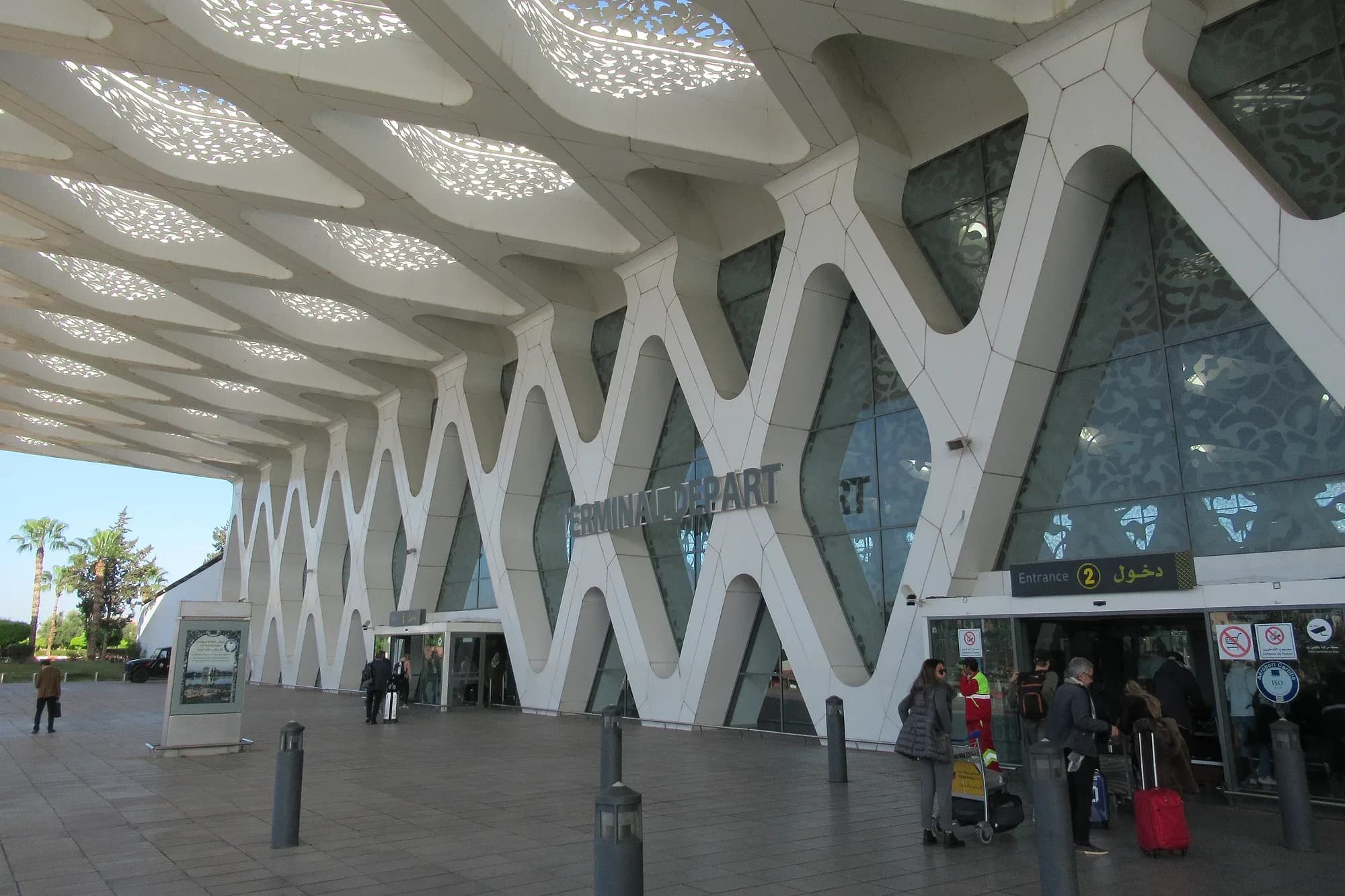 Fachada de la terminal del aeropuerto Marrakech-Menara con viajeros y maletas