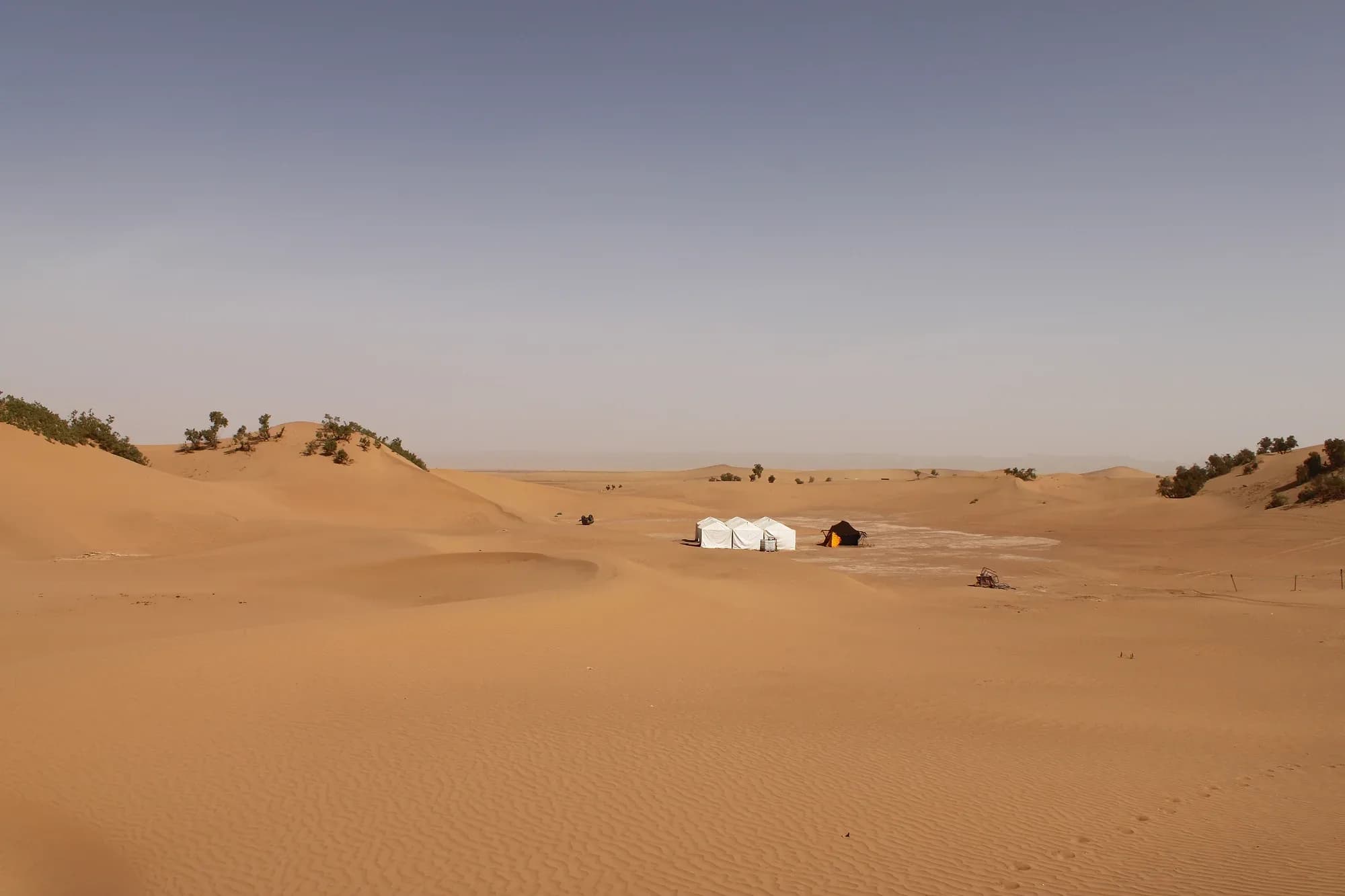 Dunas de arena con un campamento de jaimas a lo lejos cerca de Zagora