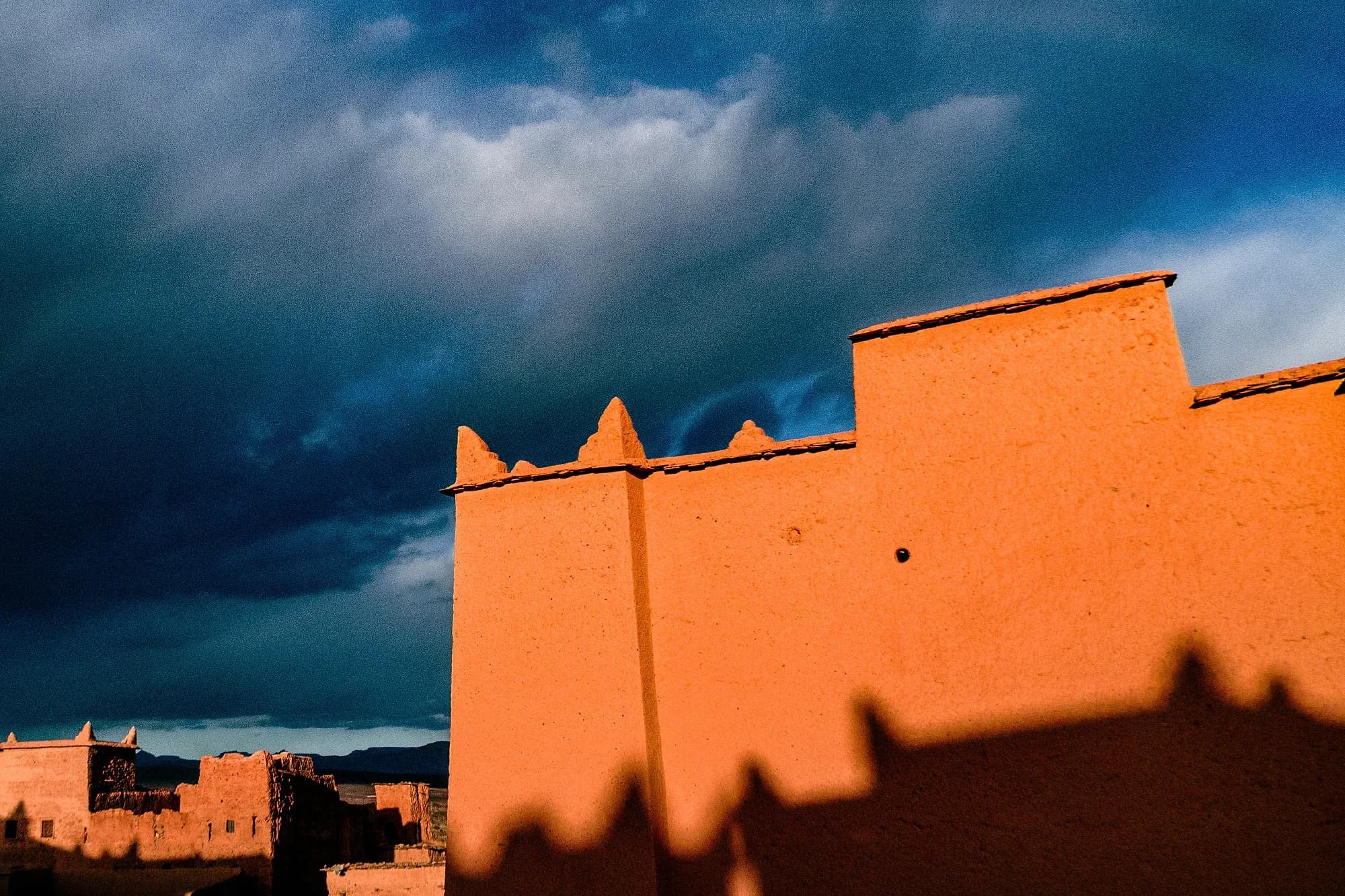 Walls of a mud-brick kasbah in N'Kob under a stormy sky