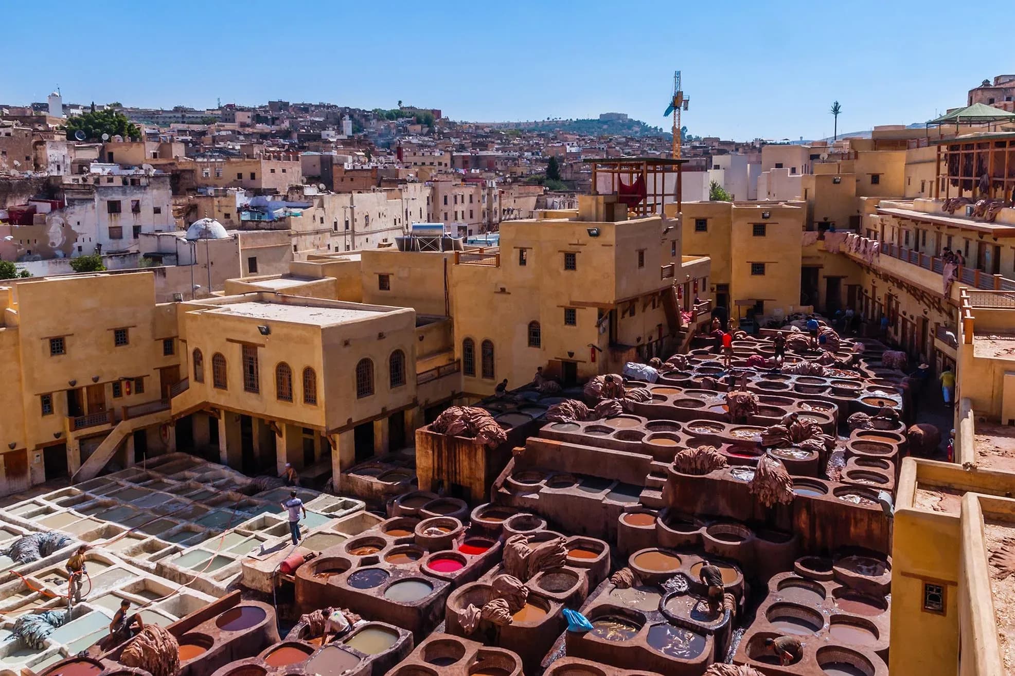 Vats of the Chouara tannery and rooftops of the Fez medina under a blue sky