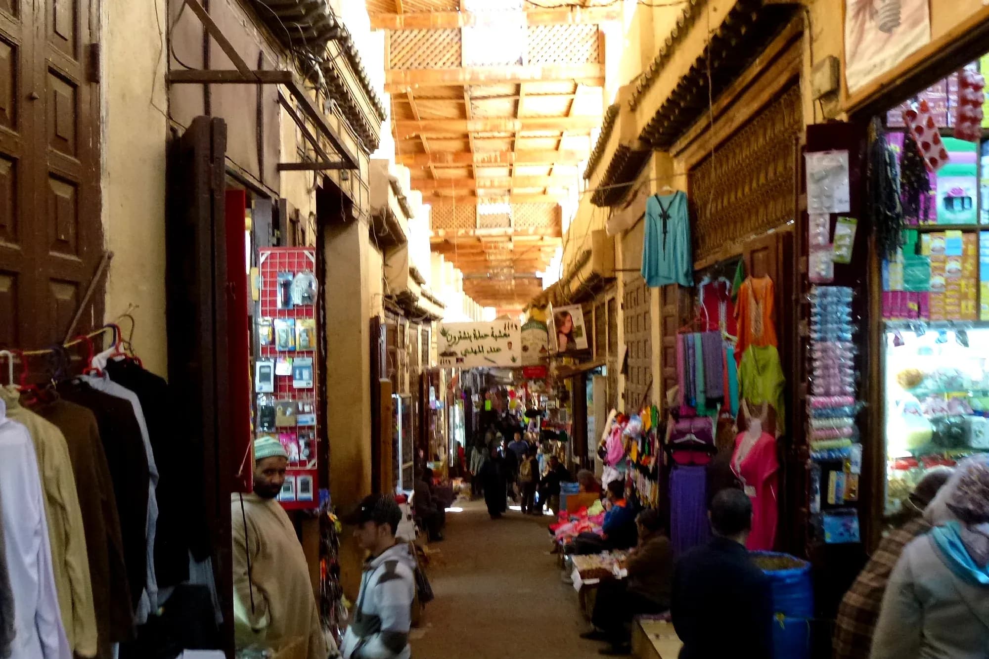 Covered shopping street in the Fez el Bali medina with clothes shops and passers-by