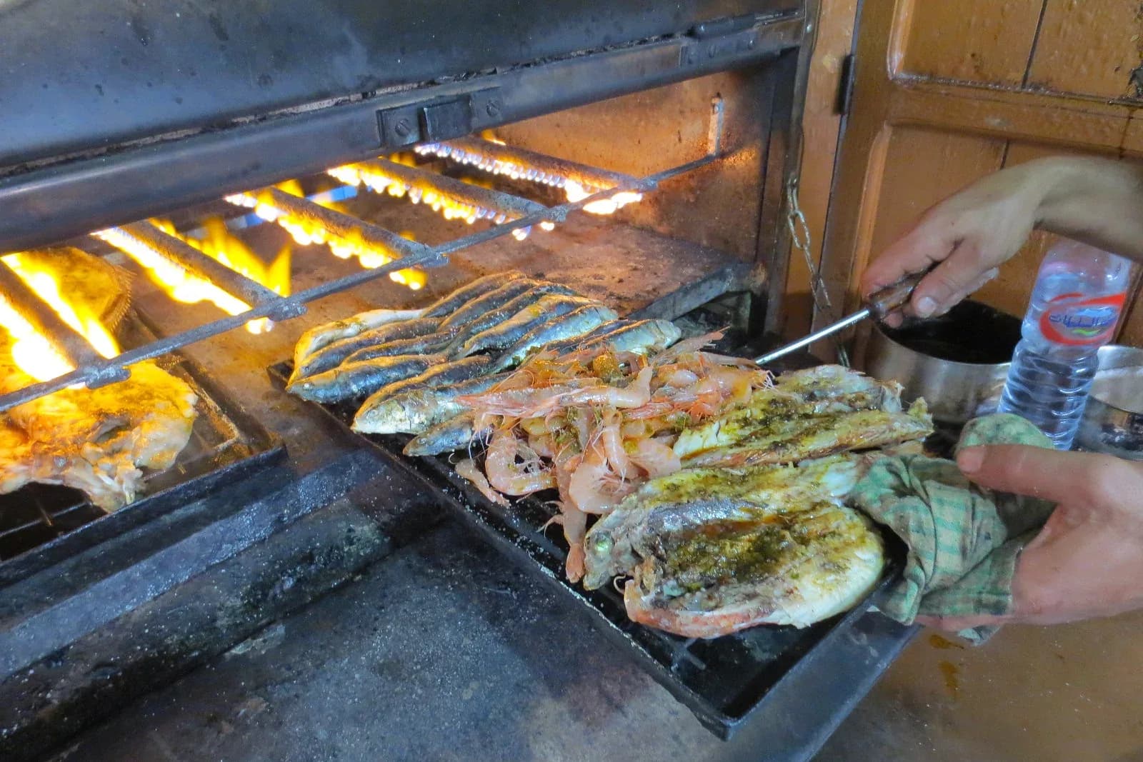 Sardines, prawns and fish cooking on a grill in Essaouira