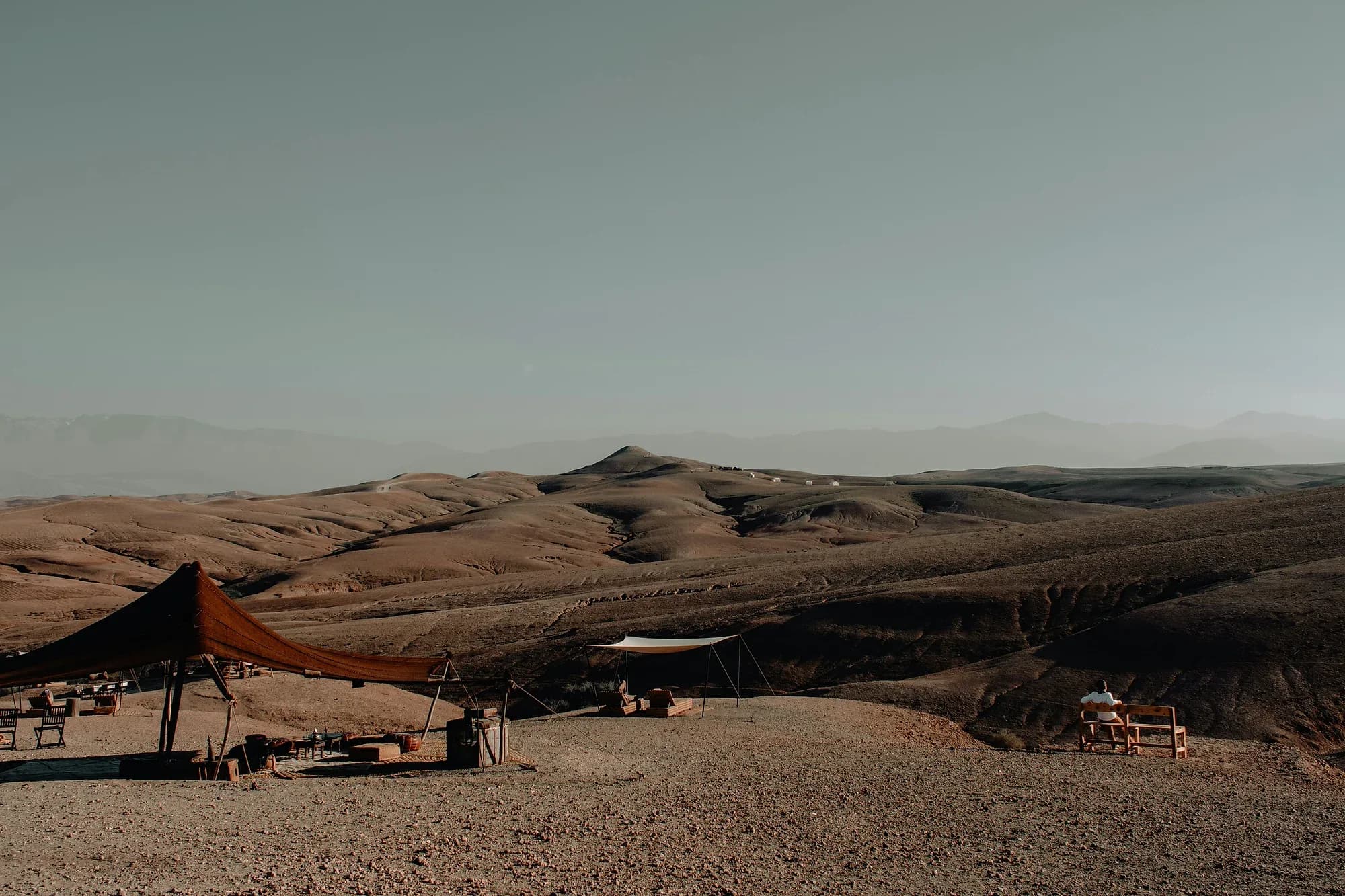 Berber tents and lounge area of a camp among the stony hills of the Agafay Desert