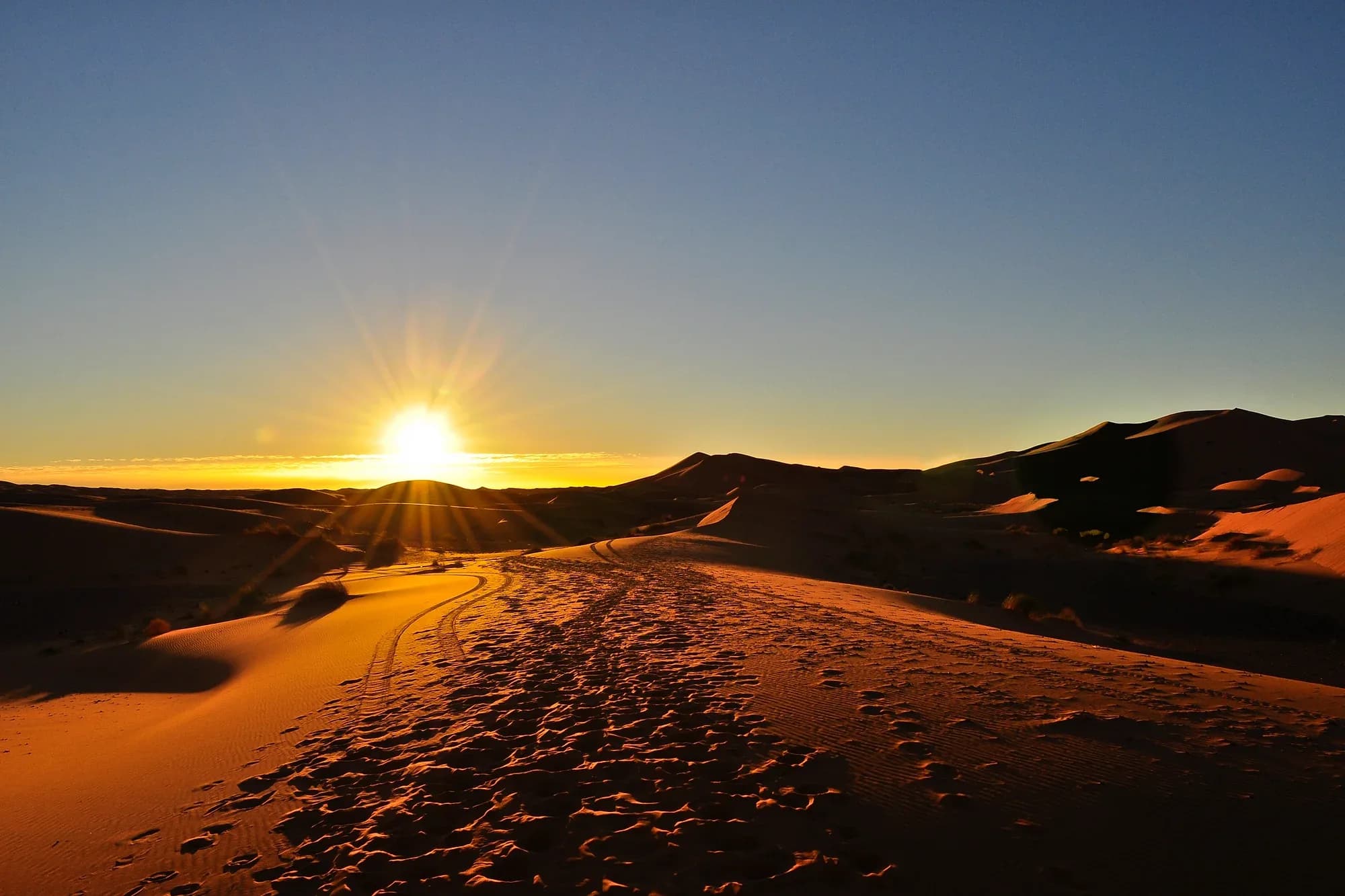 Amanecer sobre las dunas de Erg Chebbi con huellas en la arena, Merzouga