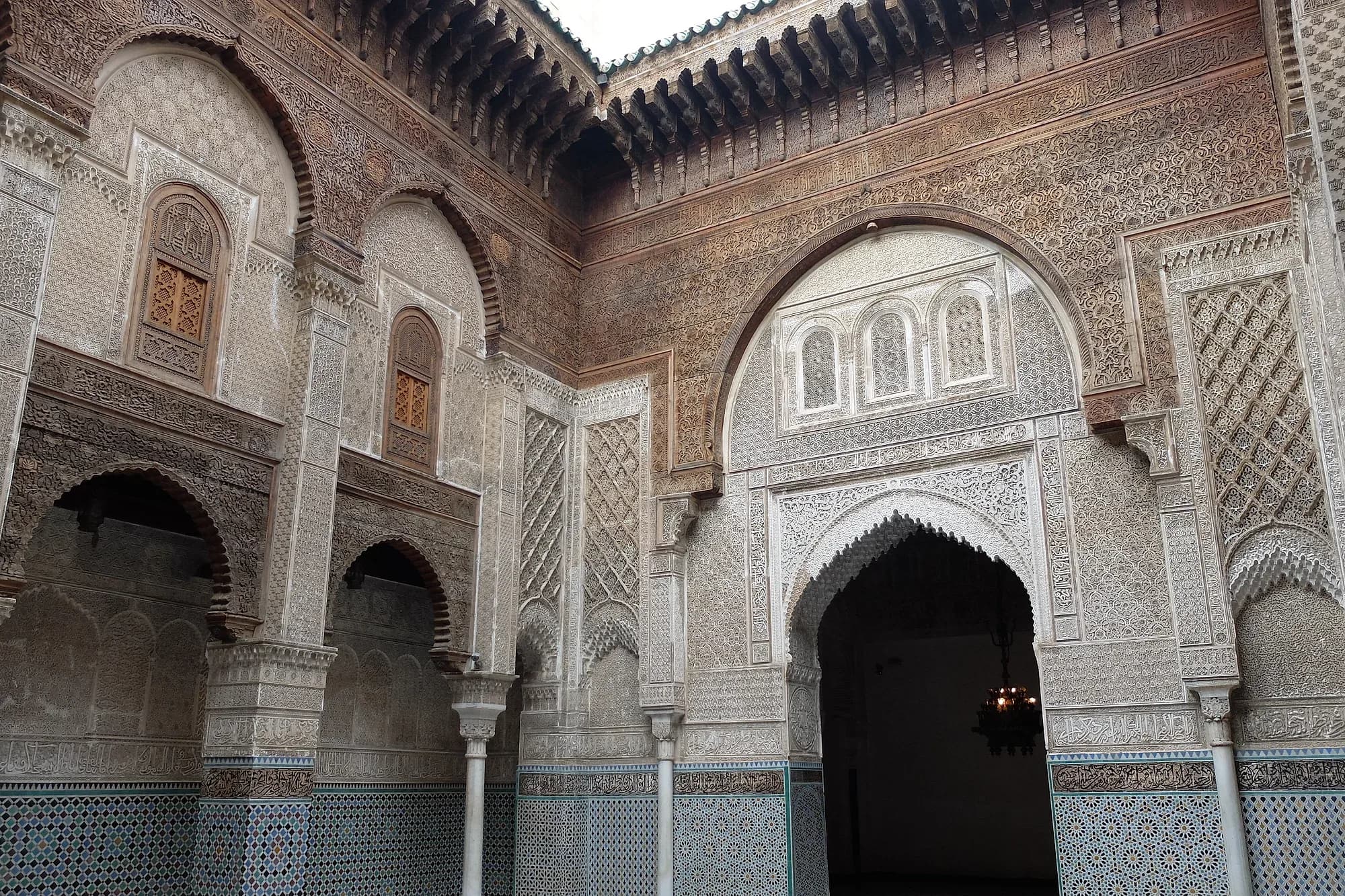 Patio de la madrasa Al-Attarine de Fez, con yesería tallada, madera de cedro y zócalo de zellige